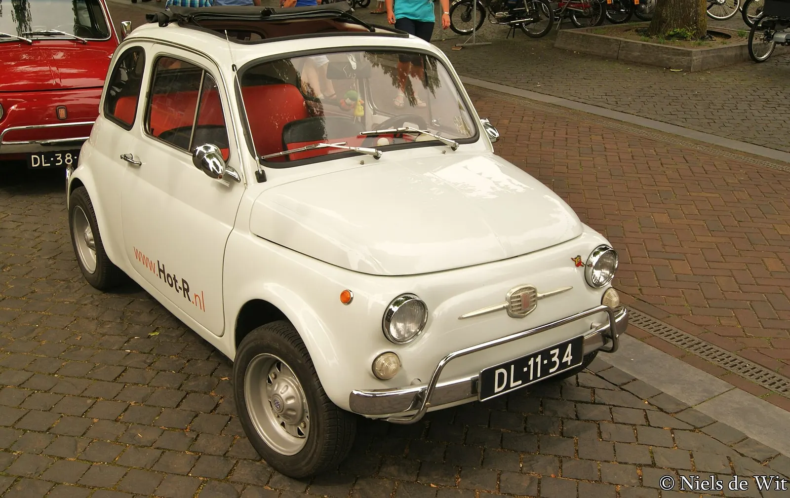 Una Fiat 500 bianca del 1967 parcheggiata su un marciapiede di mattoni